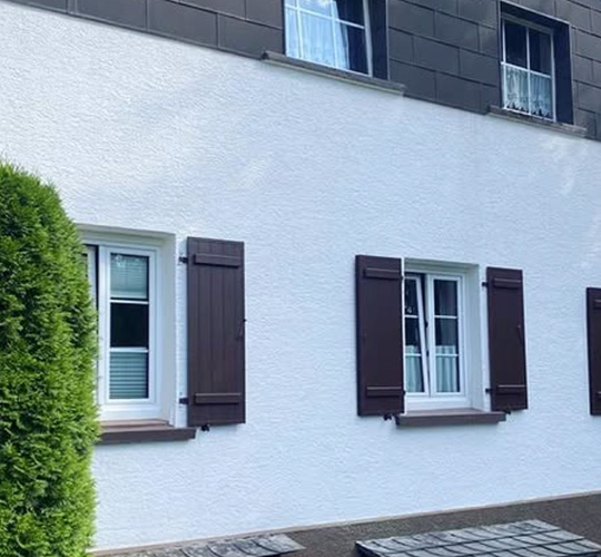 Hausfassade mit mehreren offenen Fensterläden