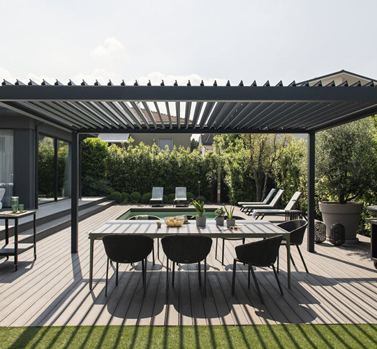 Esstisch mit Stühlen unter einer Lamellenüberdachung