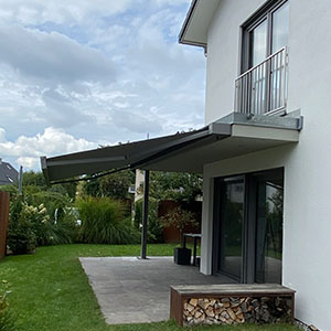 Kleine Steinfliesen-Terrasse mit ausgefahrener Markise