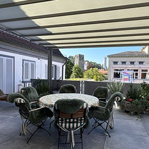 Essgruppe auf einer Terrasse überdacht von einer Pergola mit PVC-Tuch