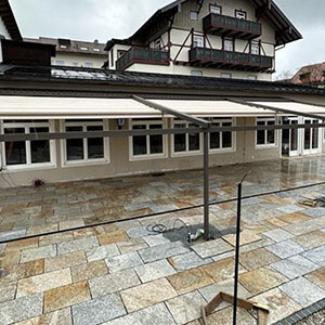 Geneigte Pergola mit PVC-Tuch über einer Steinfliesenterrasse