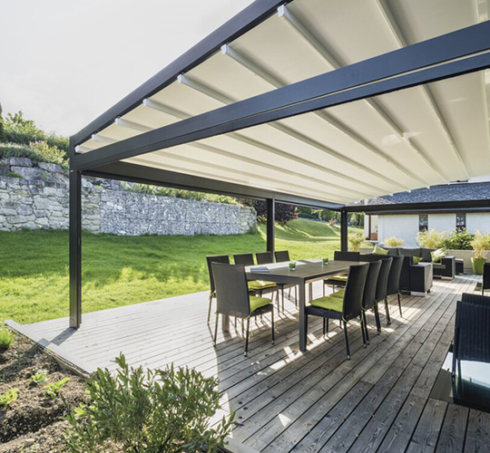 Geneigte Pergola mit Textilbespannung über Holzdielenterrasse mit Essgruppe